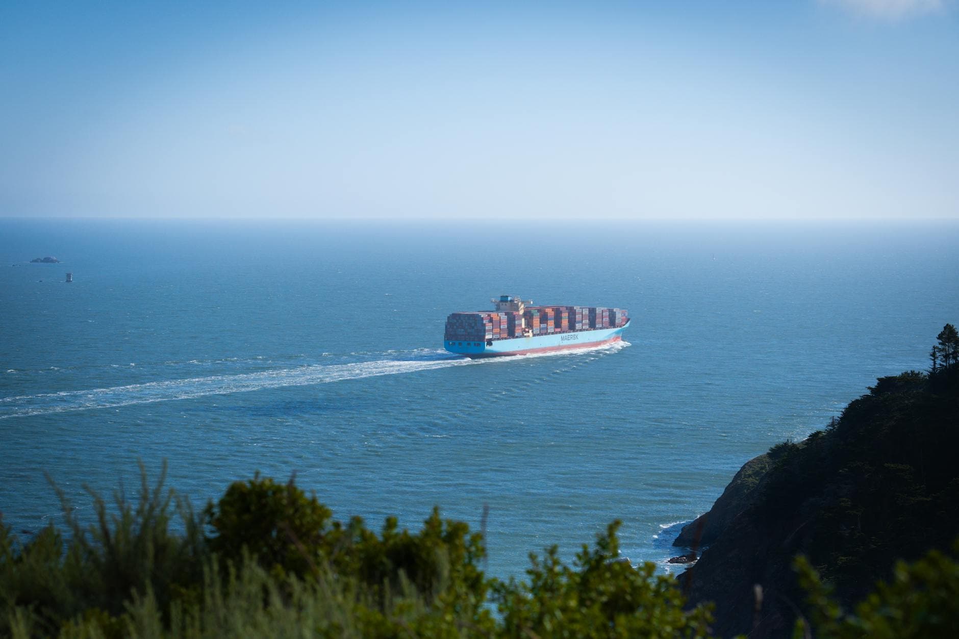 A container ship underway along the Pacific coastline near San Francisco.