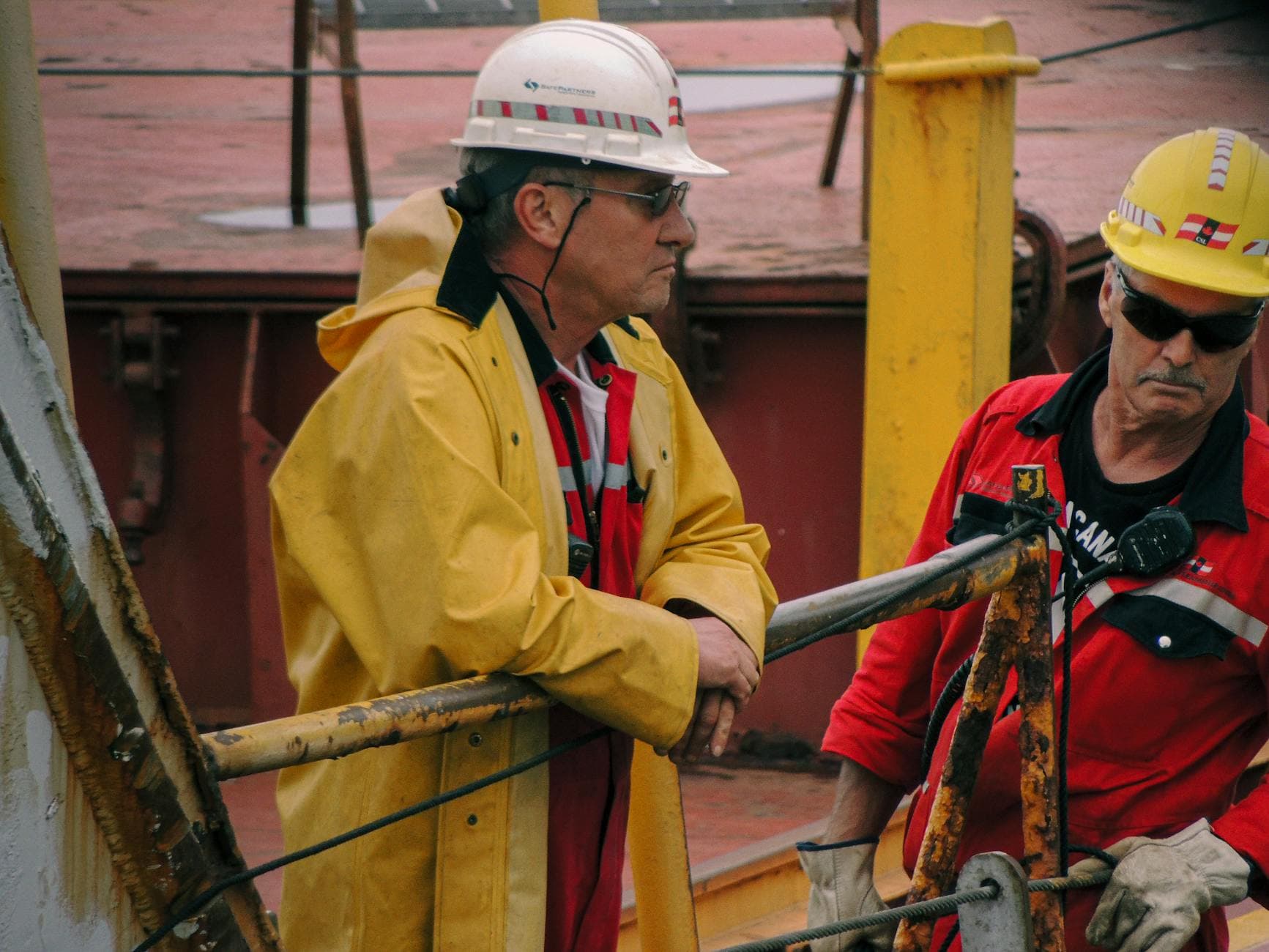 Ship crew in safety gear working on deck at an industrial port in Mackinaw City.